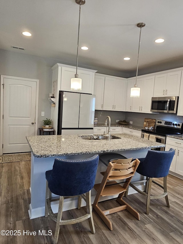 568 Transom Way, Sneads Ferry, NC 28460 - kitchen with stainless steel appliances, a sink, dark wood finished floors, white cabinets, and an island with sink