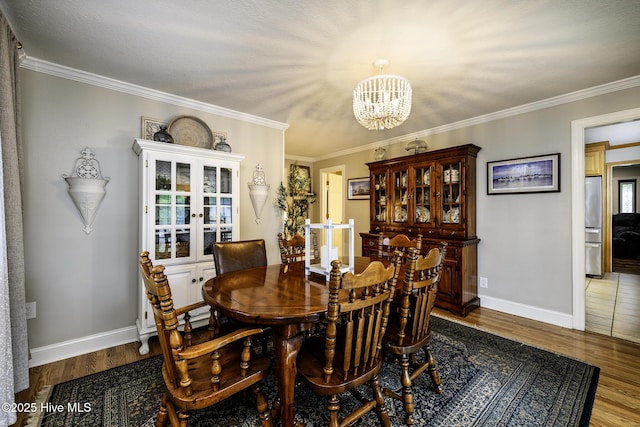 dining space featuring a chandelier, french doors, wood finished floors, baseboards, and ornamental molding