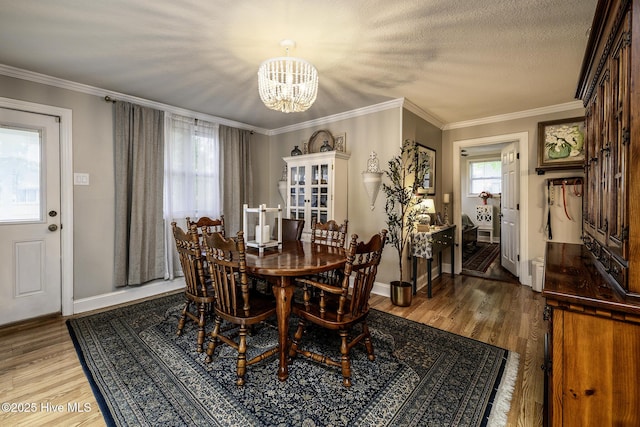 dining space with a chandelier, wood finished floors, baseboards, and crown molding