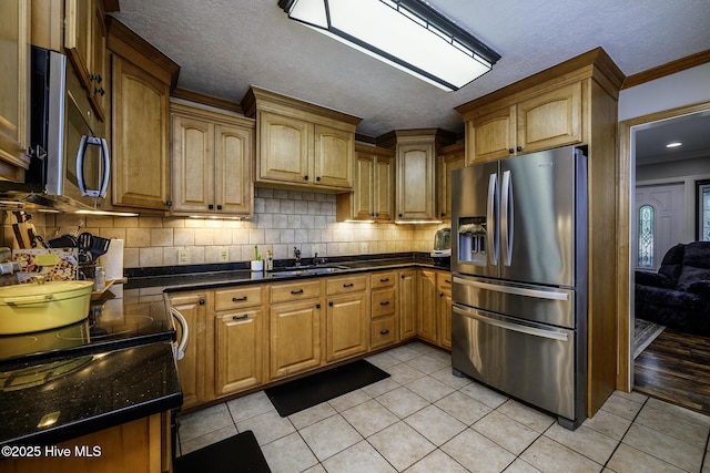 kitchen with stainless steel fridge, a sink, light tile patterned floors, ornamental molding, and tasteful backsplash