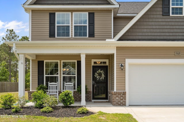 view of front of house featuring covered porch, a garage, driveway, and brick siding
