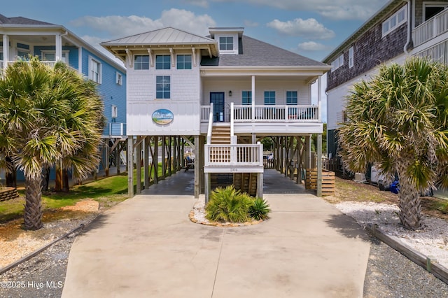 2304 W Dolphin Dr, Oak Island, NC 28465 - raised beach house with a carport, stairs, concrete driveway, a shingled roof, and covered porch
