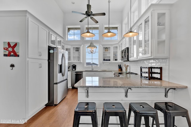 2304 W Dolphin Dr, Oak Island, NC 28465 - kitchen with stainless steel appliances, a peninsula, white cabinetry, and backsplash