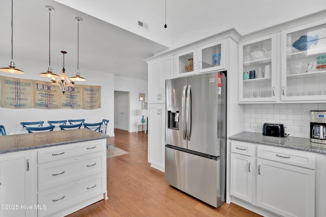 2304 W Dolphin Dr, Oak Island, NC 28465 - kitchen with stainless steel fridge, white cabinetry, light wood finished floors, decorative backsplash, and dark stone counters