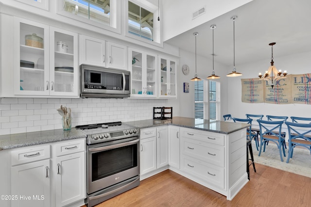 2304 W Dolphin Dr, Oak Island, NC 28465 - kitchen with stainless steel appliances, a chandelier, a peninsula, and white cabinets