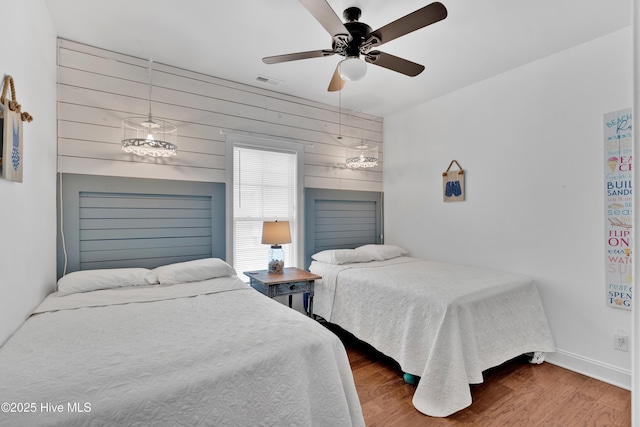 2304 W Dolphin Dr, Oak Island, NC 28465 - bedroom featuring wood finished floors, baseboards, wooden walls, and ceiling fan