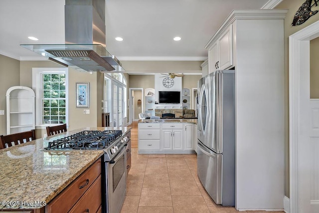 886 Hollybriar Dr SE, Bolivia, NC 28422 - kitchen featuring appliances with stainless steel finishes, island exhaust hood, ornamental molding, ceiling fan, and white cabinetry