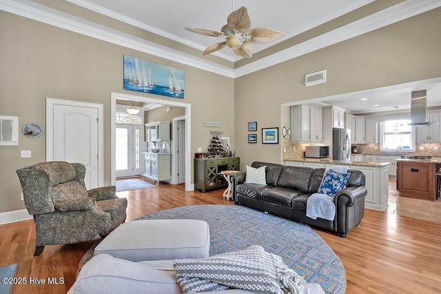 886 Hollybriar Dr SE, Bolivia, NC 28422 - living area with ornamental molding, a towering ceiling, a ceiling fan, light wood-style floors, and baseboards