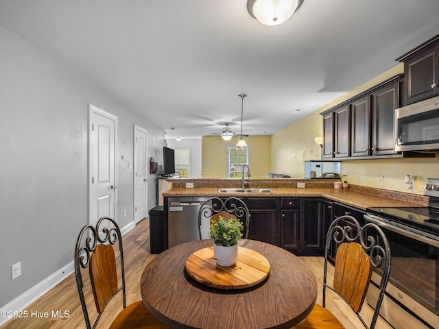 kitchen featuring a sink, appliances with stainless steel finishes, a peninsula, wood finished floors, and ceiling fan