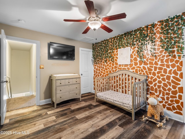 bedroom featuring wood finished floors, baseboards, a ceiling fan, and an accent wall