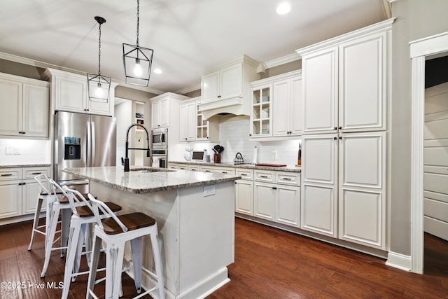 kitchen featuring stainless steel appliances, recessed lighting, decorative backsplash, glass insert cabinets, and an island with sink