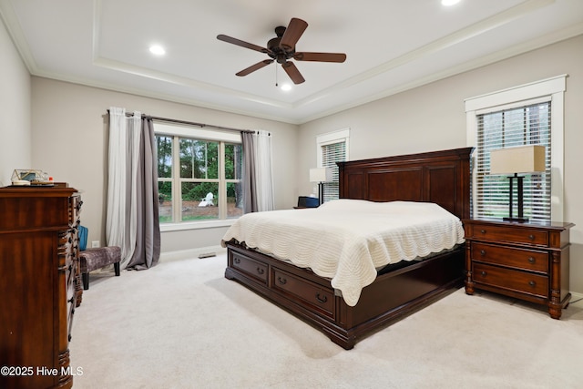 bedroom with a raised ceiling, light carpet, recessed lighting, baseboards, and crown molding