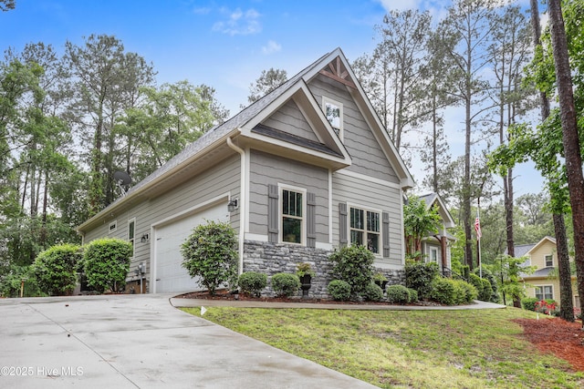 view of front of house with concrete driveway, an attached garage, stone siding, a front yard, and roof with shingles