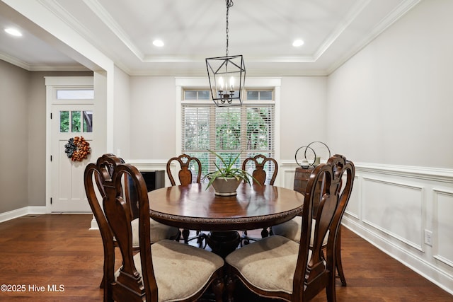 dining room featuring a chandelier, dark wood-style floors, a wainscoted wall, a tray ceiling, and crown molding