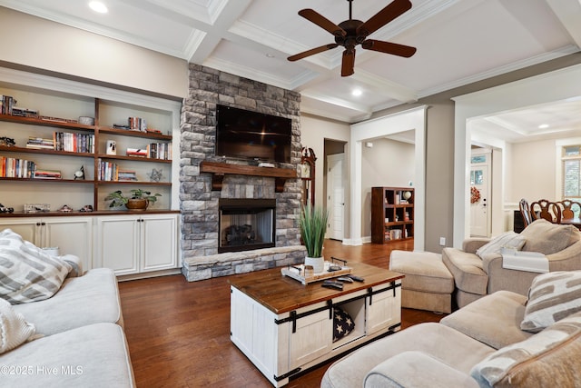 living room featuring ceiling fan, ornamental molding, beamed ceiling, dark wood finished floors, and a fireplace