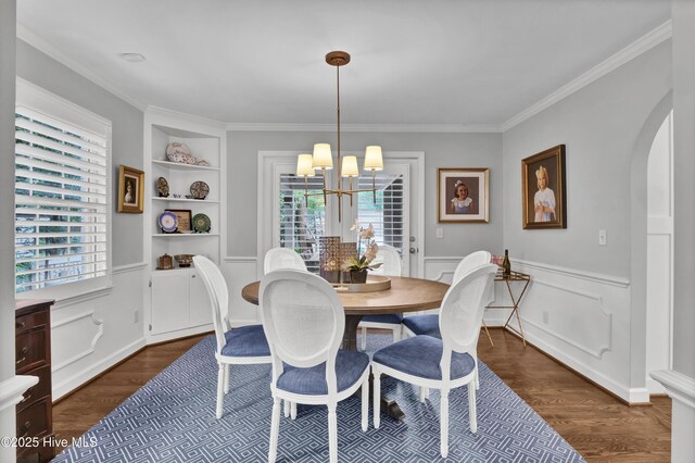 1218 Country Club Rd, Wilmington, NC 28403 - dining room featuring a chandelier, arched walkways, dark wood-style floors, crown molding, and a wainscoted wall