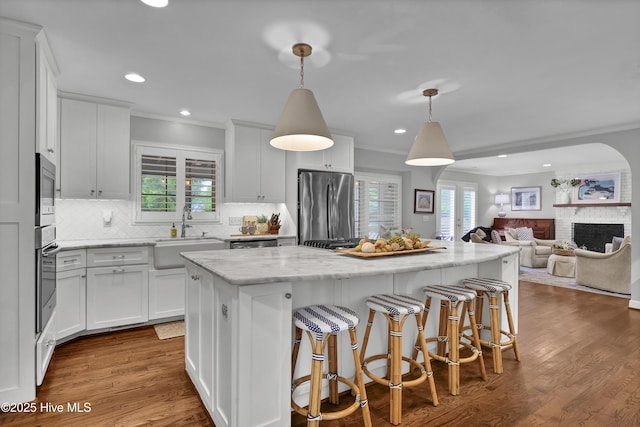 1218 Country Club Rd, Wilmington, NC 28403 - kitchen with appliances with stainless steel finishes, a sink, crown molding, a center island, and a fireplace
