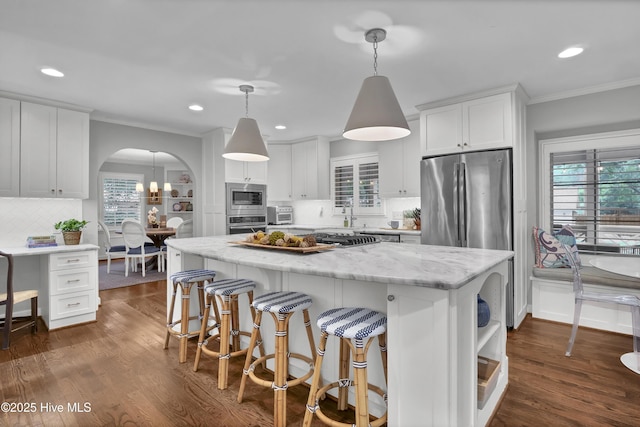 1218 Country Club Rd, Wilmington, NC 28403 - kitchen with appliances with stainless steel finishes, ornamental molding, arched walkways, white cabinets, and a center island