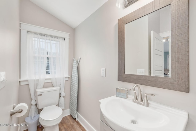 half bathroom with vaulted ceiling, toilet, baseboards, wood finished floors, and vanity