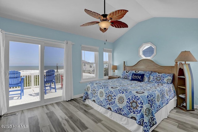 bedroom with access to exterior, vaulted ceiling, wood finished floors, ceiling fan, and a water view