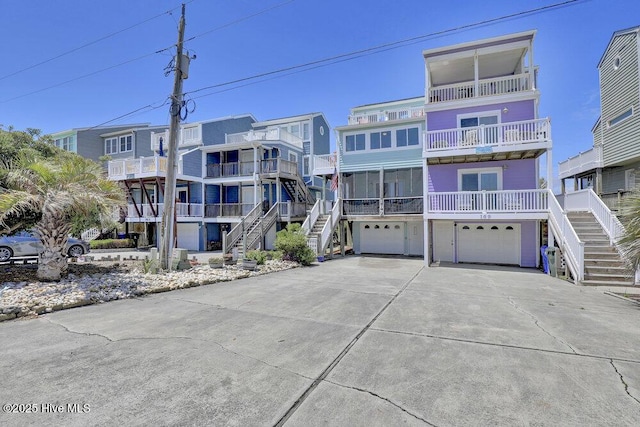view of apartment building / complex featuring stairway, an attached garage, and concrete driveway