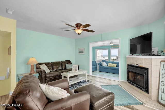 living room featuring wood finished floors, ceiling fan, and a fireplace