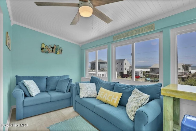 living area featuring wood finished floors, crown molding, a ceiling fan, and baseboards