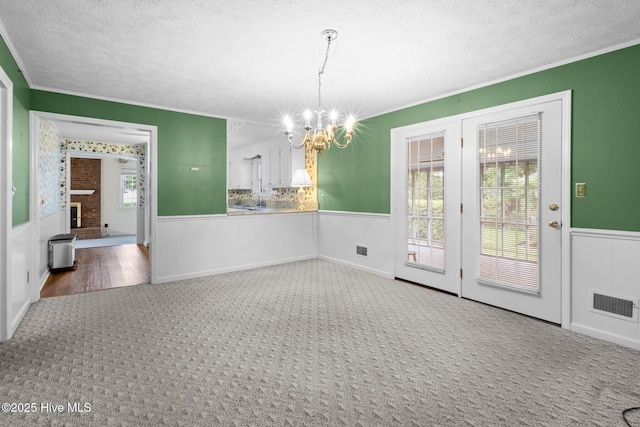 330 Breckenridge Dr, Wilmington, NC 28412 - unfurnished dining area featuring carpet floors, a chandelier, wainscoting, crown molding, and a textured ceiling
