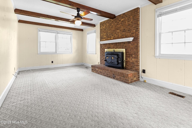 330 Breckenridge Dr, Wilmington, NC 28412 - unfurnished living room with ceiling fan, a wood stove, beam ceiling, carpet floors, and healthy amount of natural light
