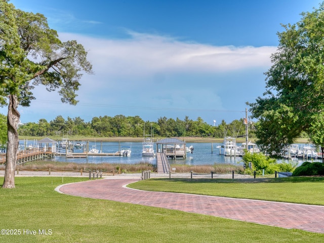 view of home's community featuring a dock, a lawn, and a water view