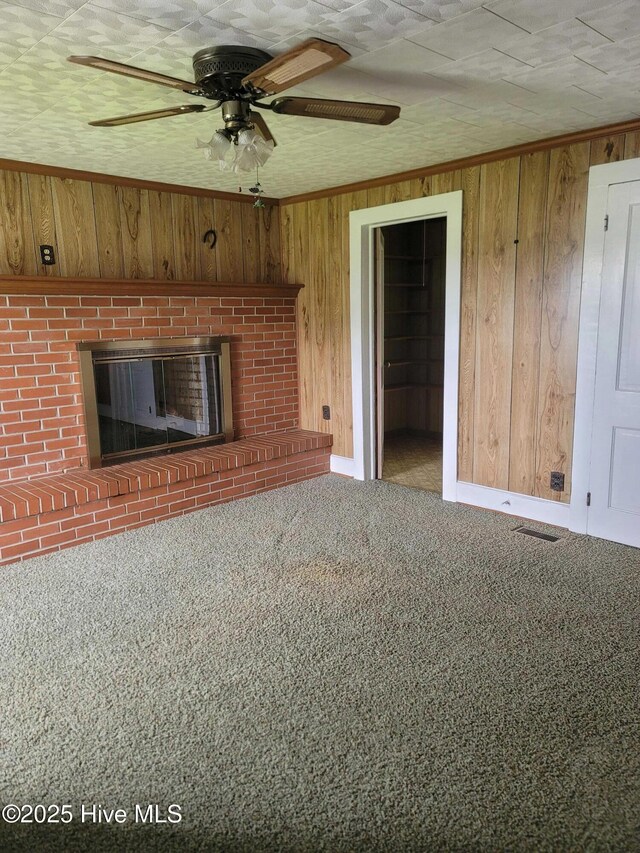 146 Gliden Rd, Hobbsville, NC 27946 - unfurnished living room with wood walls, carpet floors, a ceiling fan, and a brick fireplace