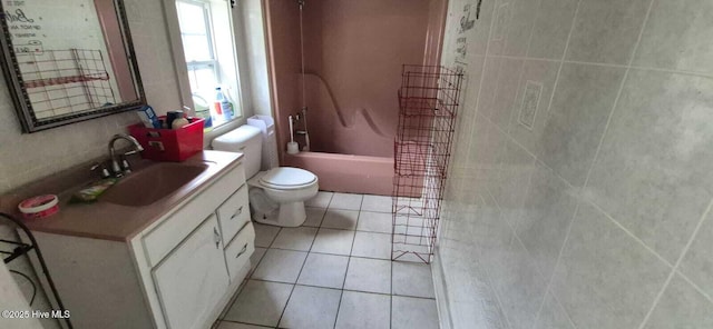 full bathroom with toilet, vanity, tile patterned floors, washtub / shower combination, and tile walls