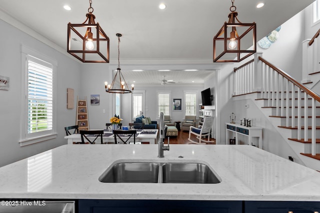 kitchen featuring a sink, open floor plan, recessed lighting, hanging light fixtures, and light stone counters