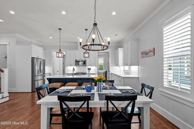 dining space with crown molding, a chandelier, recessed lighting, dark wood-style flooring, and stairs