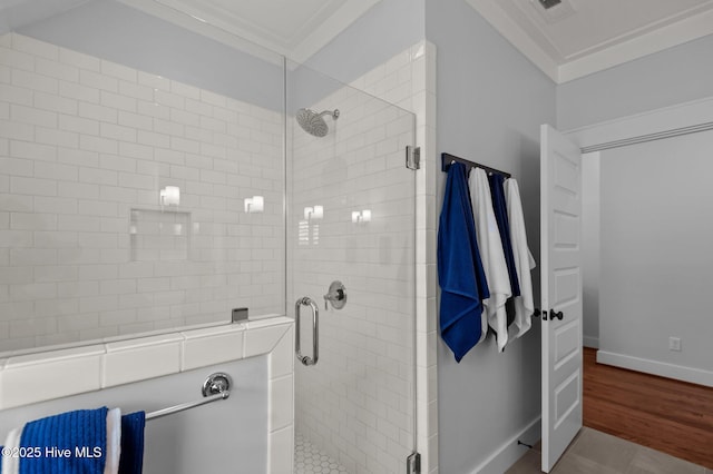 bathroom featuring a shower stall, baseboards, crown molding, and wood finished floors