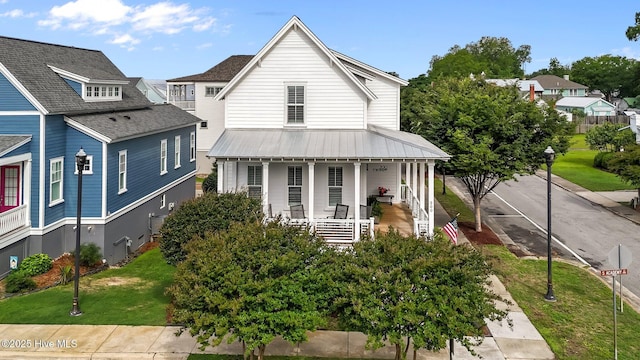 view of front of property with a porch, a front yard, metal roof, and roof with shingles