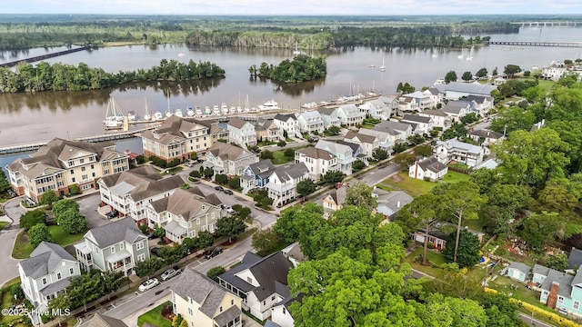 aerial view of residential area featuring a nearby body of water and a heavily wooded area