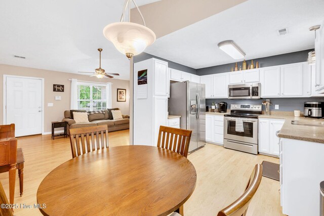 7394 Red Stone Ct, Leland, NC 28451 - kitchen with appliances with stainless steel finishes, light wood-type flooring, white cabinetry, ceiling fan, and a sink