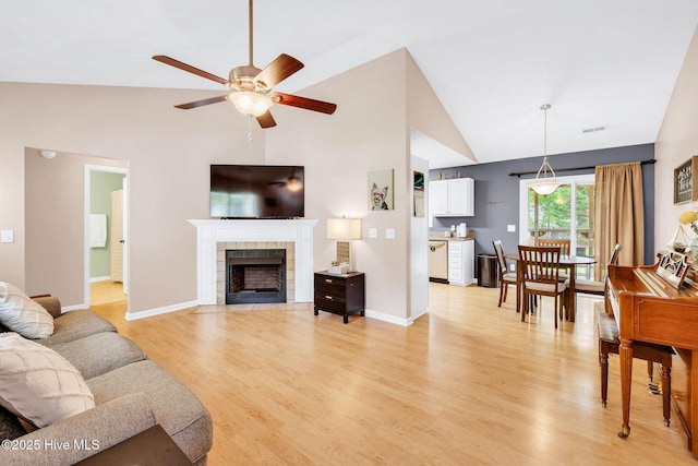 7394 Red Stone Ct, Leland, NC 28451 - living area with a ceiling fan, light wood-style floors, a tile fireplace, high vaulted ceiling, and baseboards