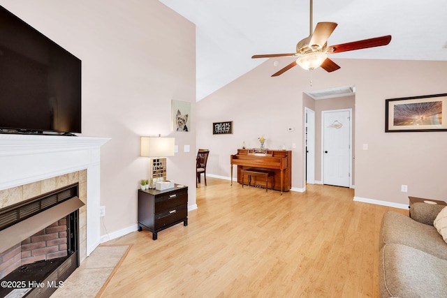 7394 Red Stone Ct, Leland, NC 28451 - living area with light wood-type flooring, ceiling fan, a tile fireplace, baseboards, and high vaulted ceiling