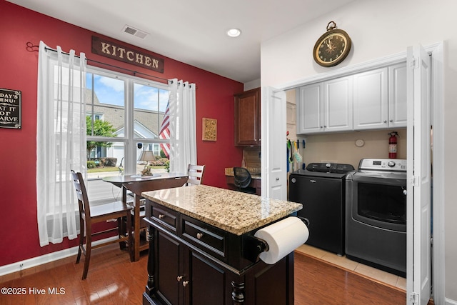 4007 Norseman Loop Unit 5, Southport, NC 28461 - kitchen featuring washing machine and clothes dryer, white cabinets, light stone counters, a center island, and wood finished floors