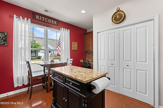 4007 Norseman Loop Unit 5, Southport, NC 28461 - kitchen featuring light wood-style floors, light stone counters, recessed lighting, a center island, and dark cabinetry