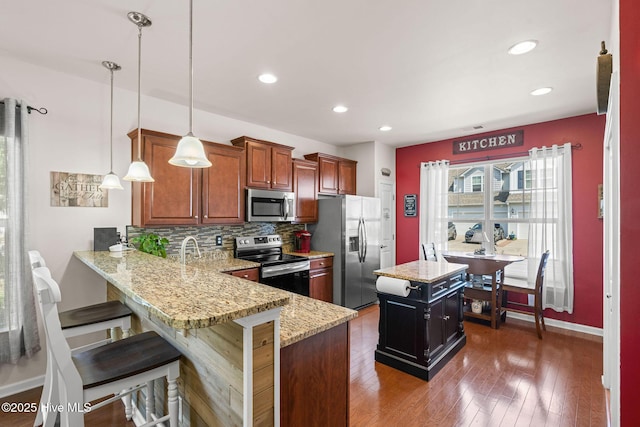 4007 Norseman Loop Unit 5, Southport, NC 28461 - kitchen featuring appliances with stainless steel finishes, tasteful backsplash, a peninsula, a center island, and pendant lighting