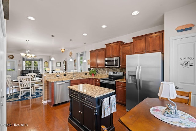 4007 Norseman Loop Unit 5, Southport, NC 28461 - kitchen with appliances with stainless steel finishes, a peninsula, a chandelier, a sink, and backsplash