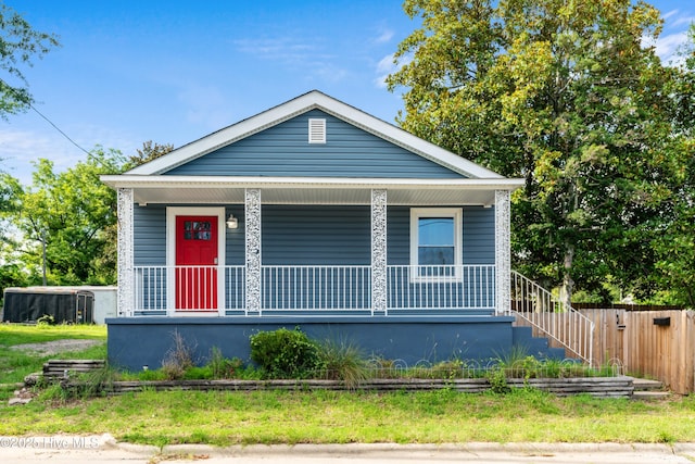 shotgun-style home with a porch and fence