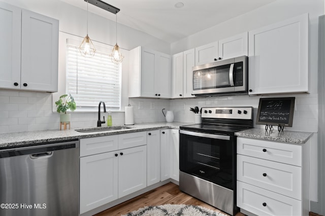 kitchen with appliances with stainless steel finishes, a sink, white cabinetry, and decorative backsplash
