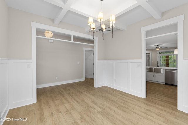 spare room with a sink, coffered ceiling, beam ceiling, wainscoting, and light wood-type flooring