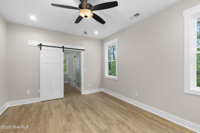 unfurnished bedroom featuring a barn door, light wood-style flooring, baseboards, recessed lighting, and ceiling fan
