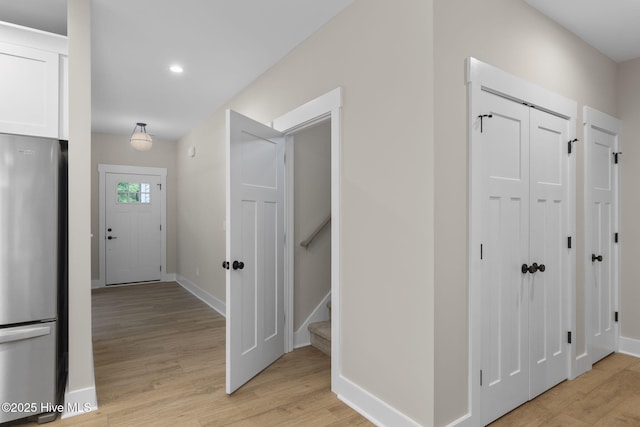 corridor with light wood-style floors, baseboards, stairway, and recessed lighting