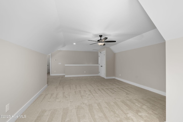 bonus room featuring lofted ceiling, light colored carpet, a ceiling fan, and baseboards